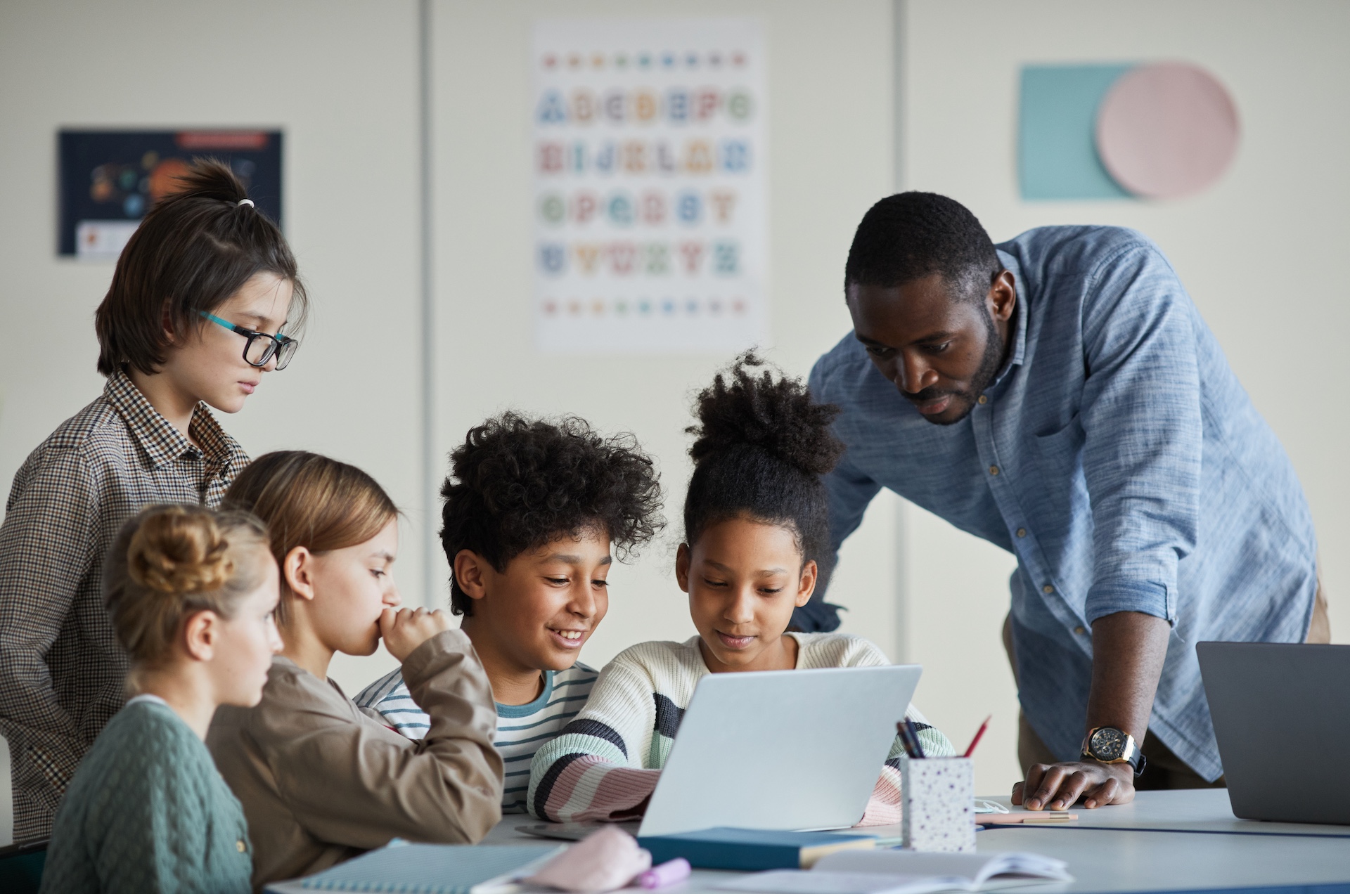 Children and a teacher looking at a computer