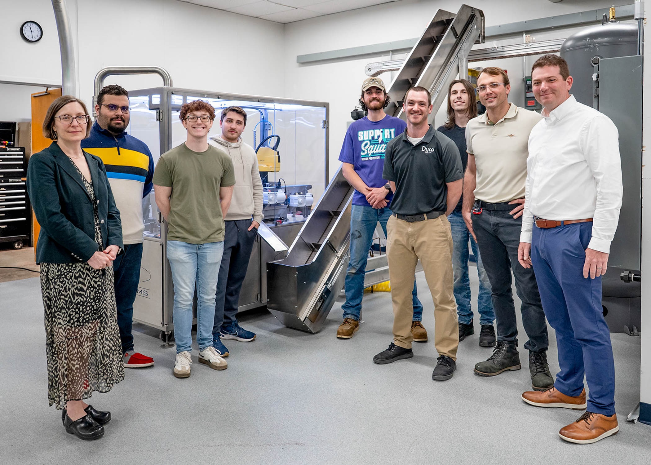 A group of people stand in front of a 9-foot incline conveyor