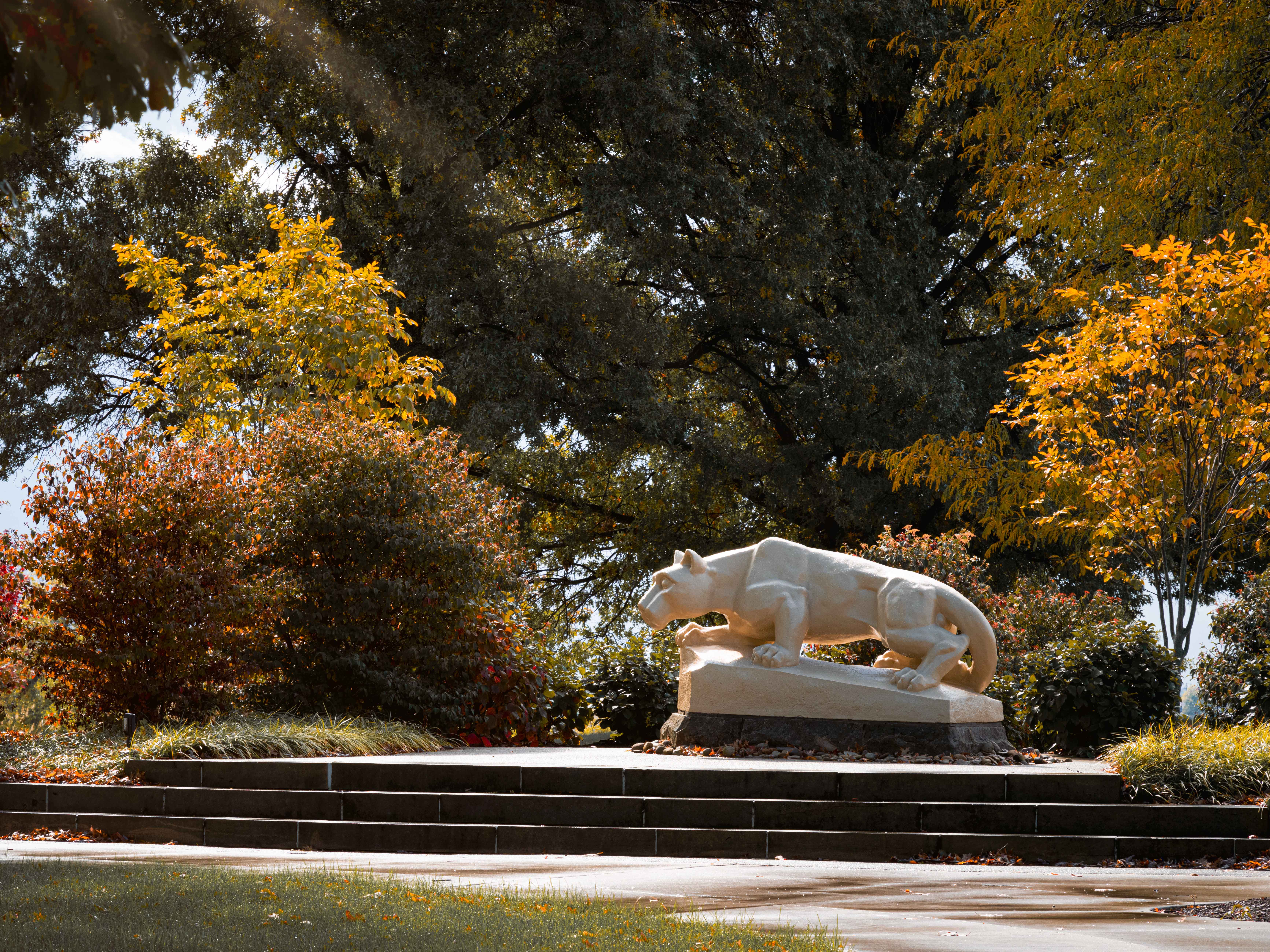 The Nittany Lion Shrine at Penn State Fayette stands surrounded by foliage.