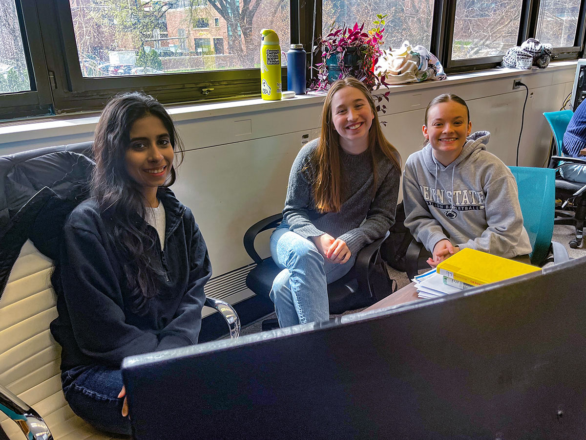 Graduate student Harman and undergraduates Laura and Maria work together at a computer on a research project about waste management.