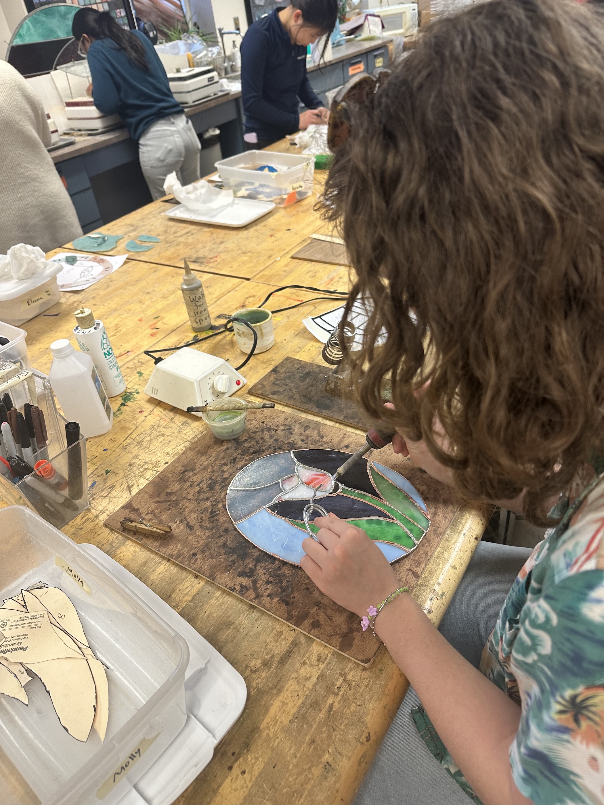 Person working on stained glass in a workshop.