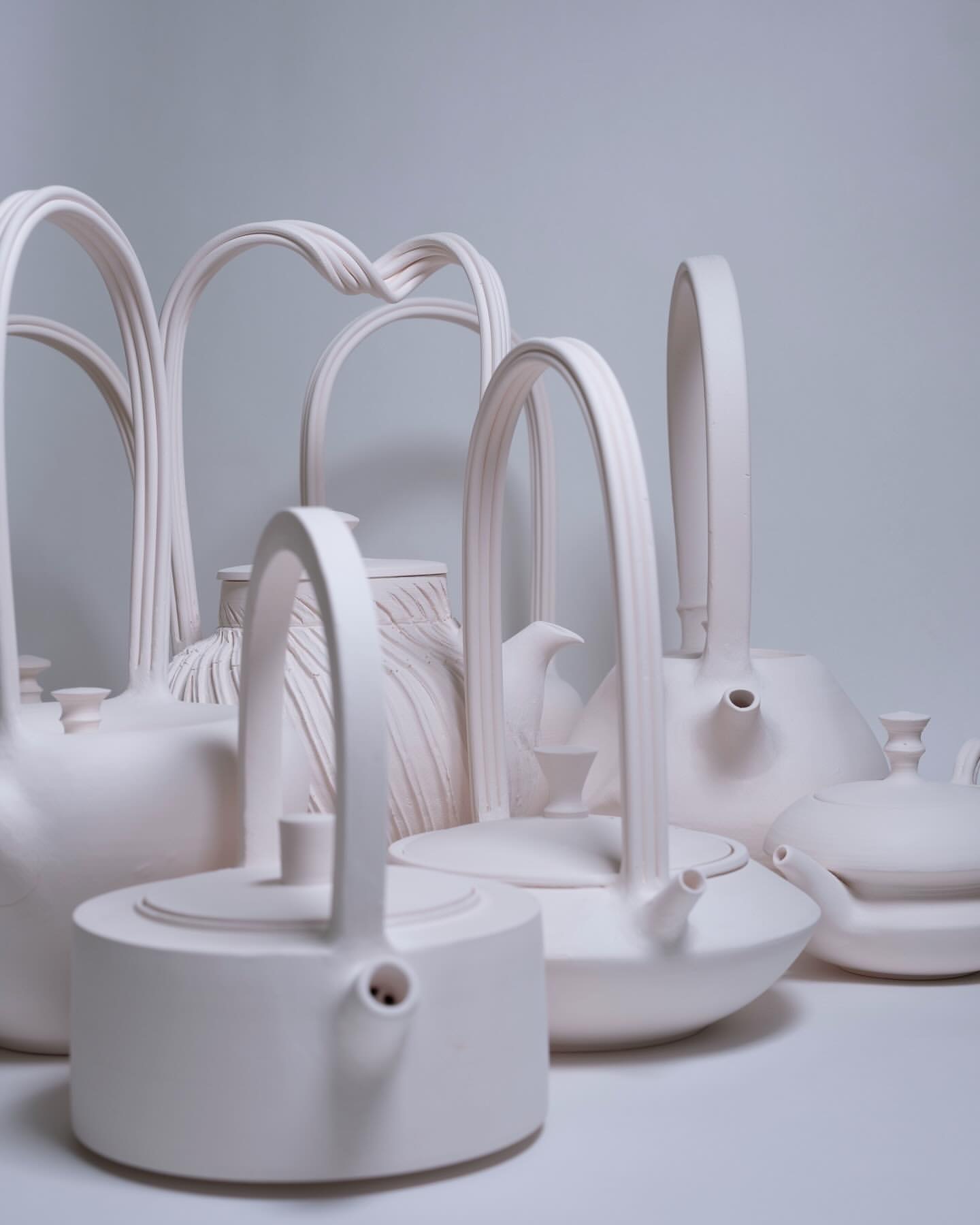Pieces of ceramic artwork with a white background. Ceramic items look to be tea pots in various sizes and shapes.
