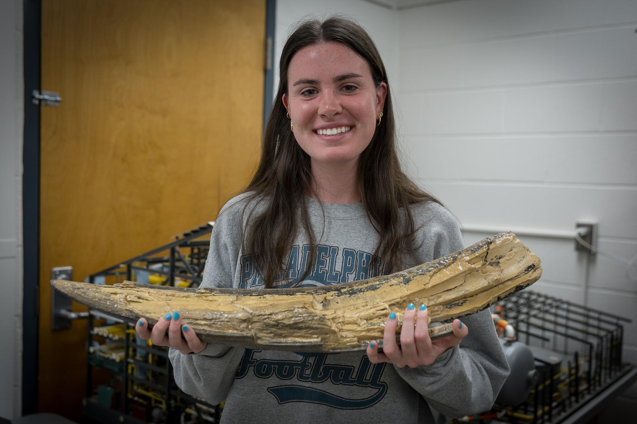 Geosciences student Kaitlin Dasovich holds mastodon tusk