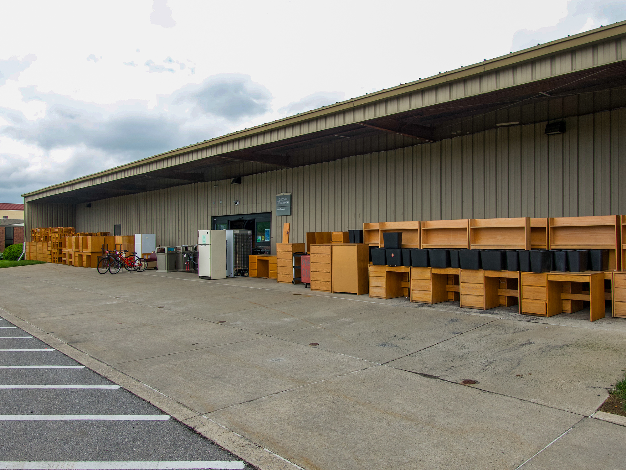 The exterior of Lion Surplus, a beige building surrounded by crates and boxes.