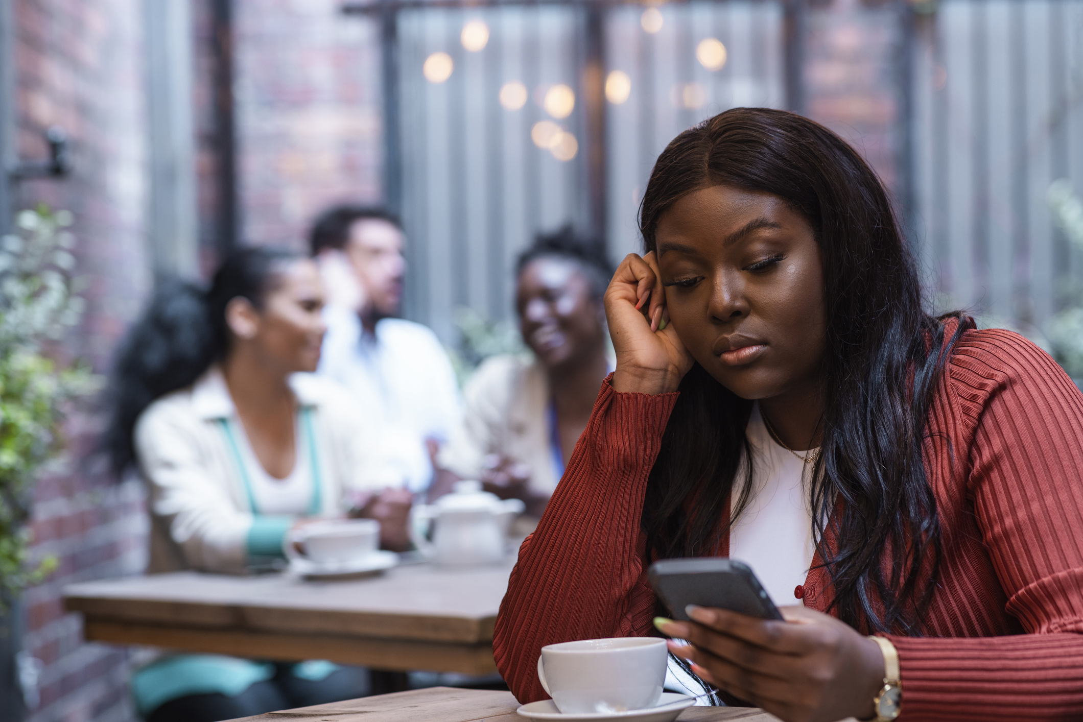 Person in coffee shop on phone looking bored