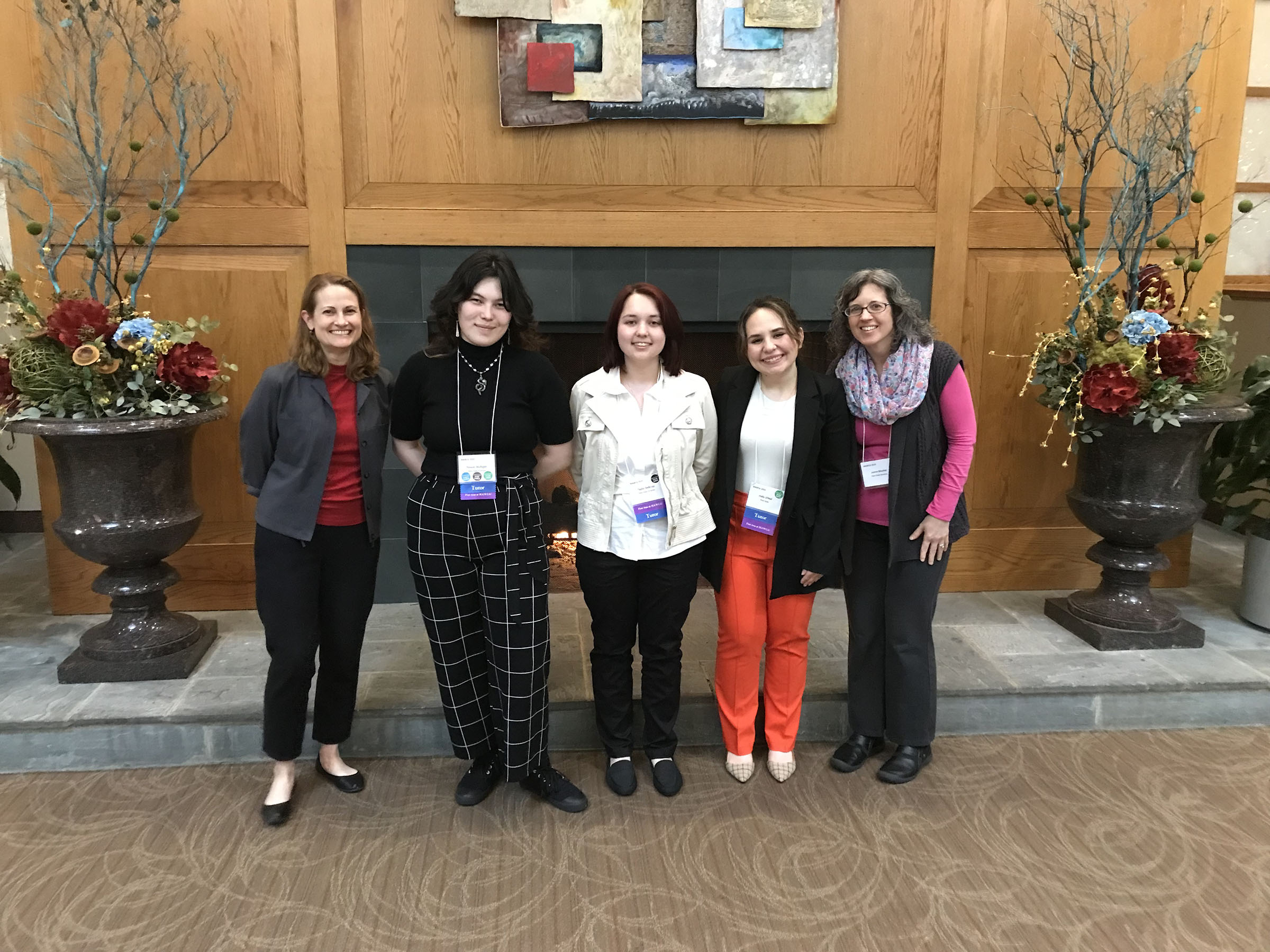 Students and chaperones pose for a photo togehter in front of a fireplace 