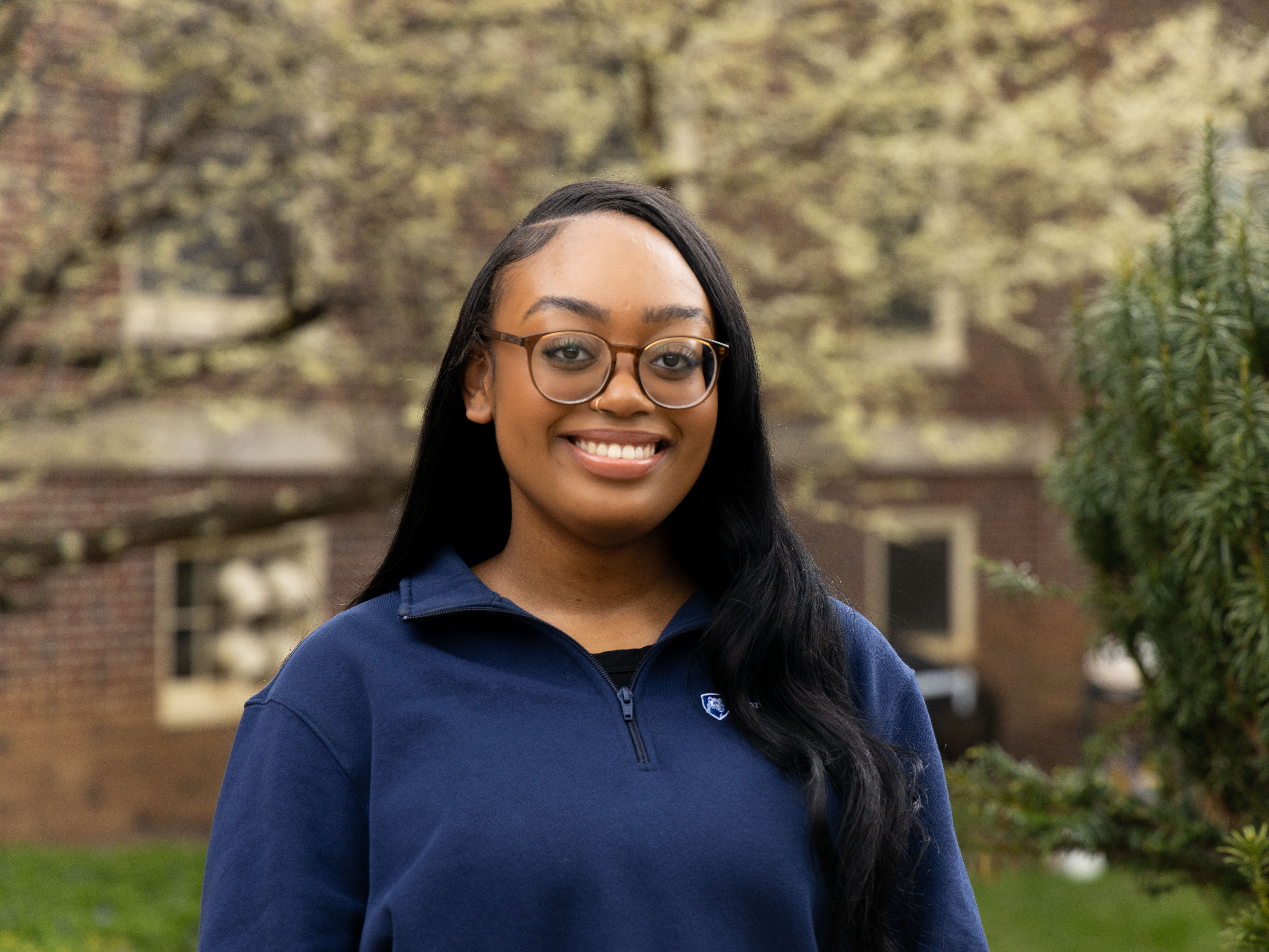 Kyla Pritchett stands in front of a flowering tree outside West Halls at Penn State University Park. 