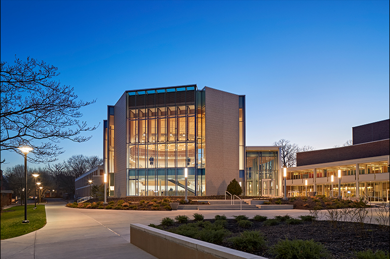 An outside view of a recital hall with grand windows photographed at sunset