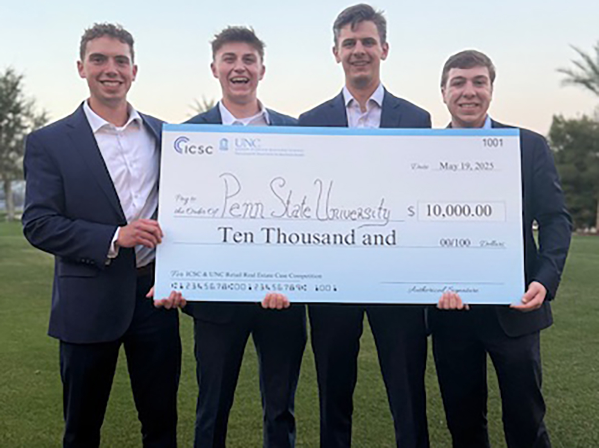 Four young men in suits hold an oversized check for 10 thousand dollars