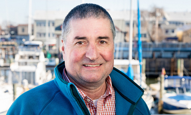 Penn State chemical engineering alumnus and Chesapeake Bay Program Director Dana Aunkst in blue fleece with a Chesapeake Bay boat dock behind him. 