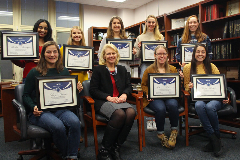 A group of undergraduate female students and a female administrator pose with certificates. 