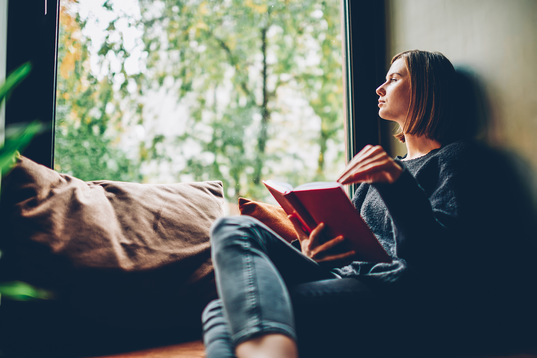 A woman reading a book on a window bench