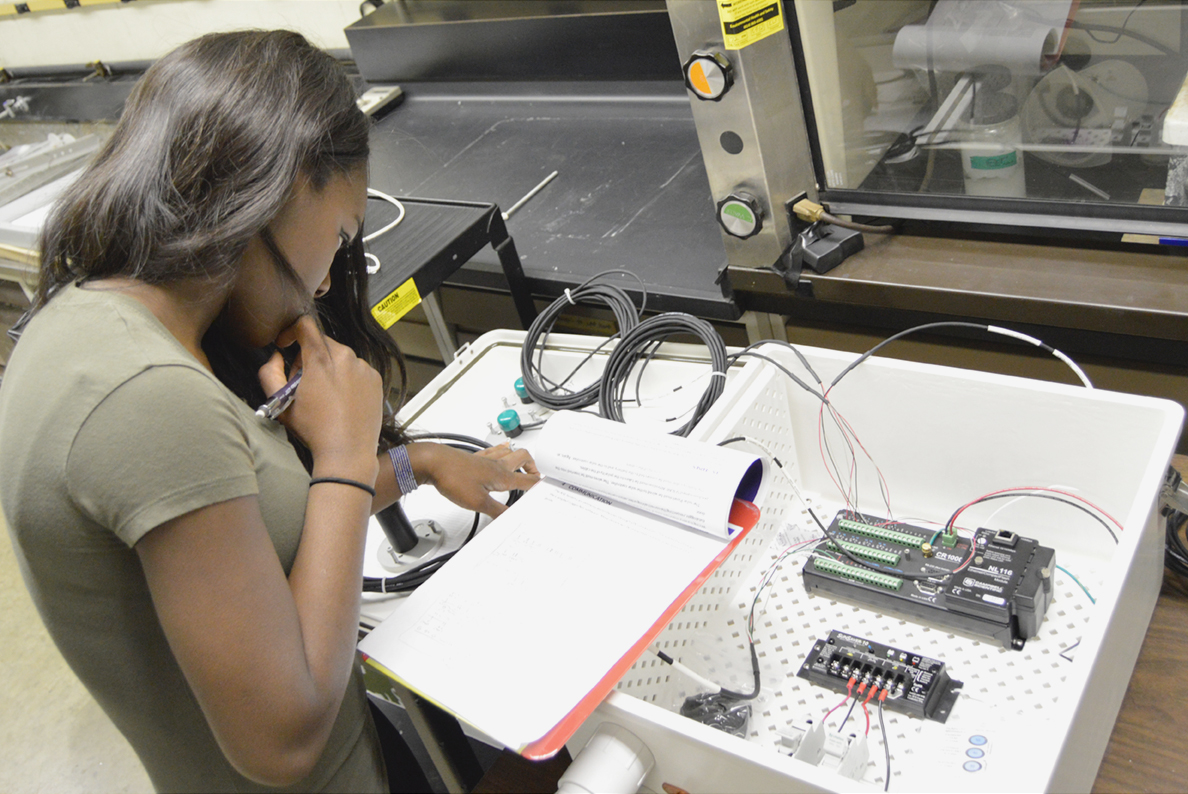 Undergraduate student Worlasie Djameh inspects the wiring configuration of the All-Seeing Eye device prior to installation.