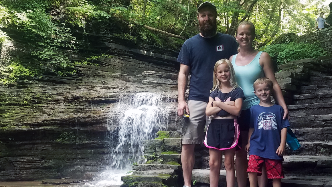 Family posing in front of a waterfall