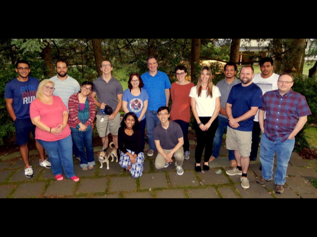 A diverse group of people stand and smile for a photographer.