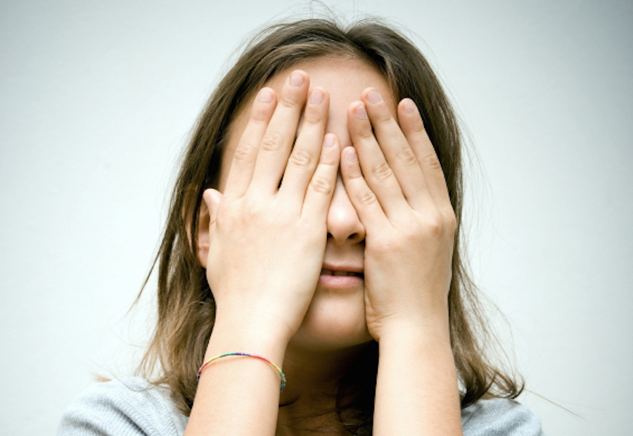 Child covering face with hands