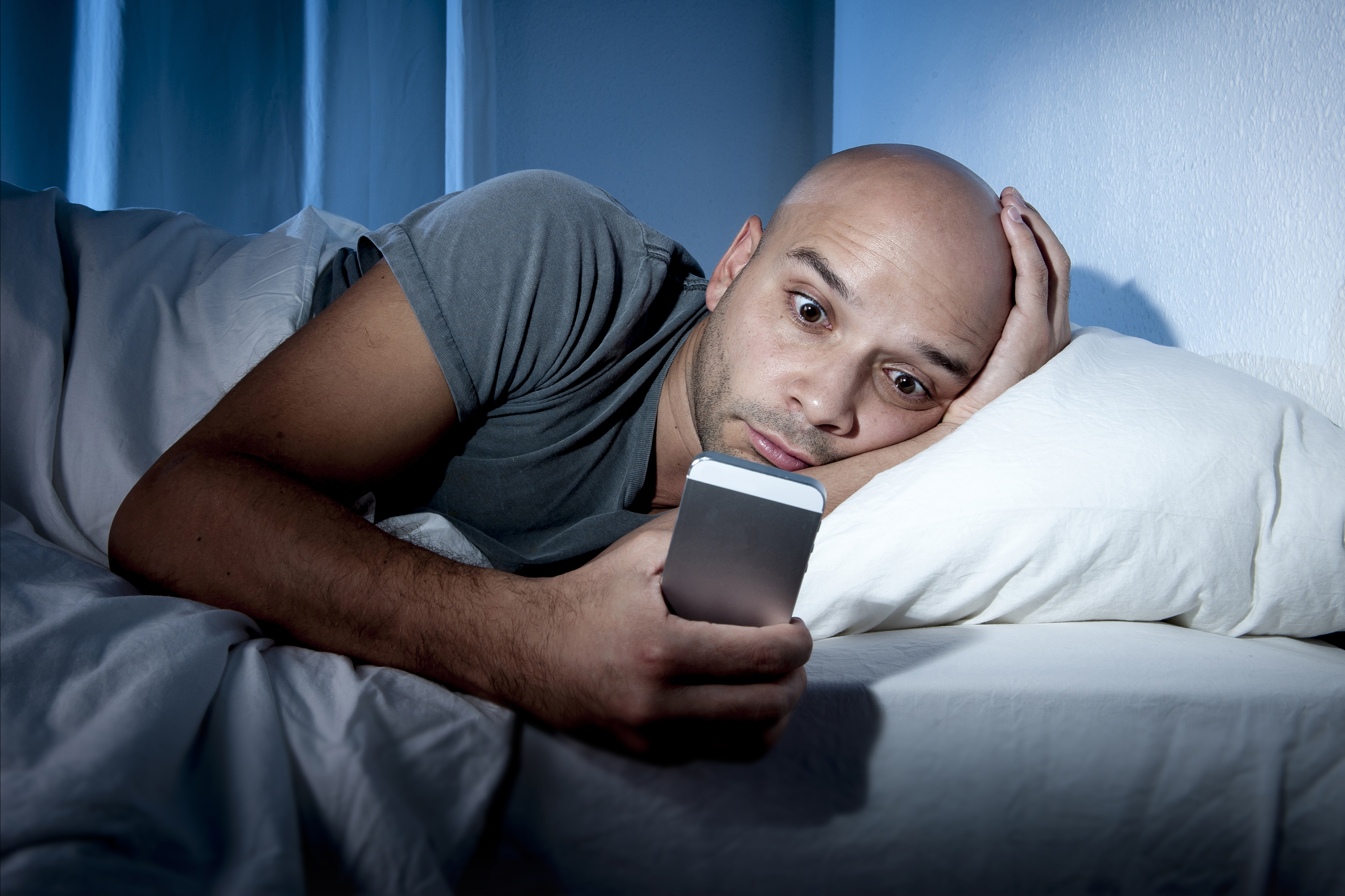 Man awake in bed with cell phone