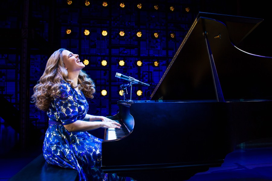 A woman throws her head back and sings while playing at a grand piano.