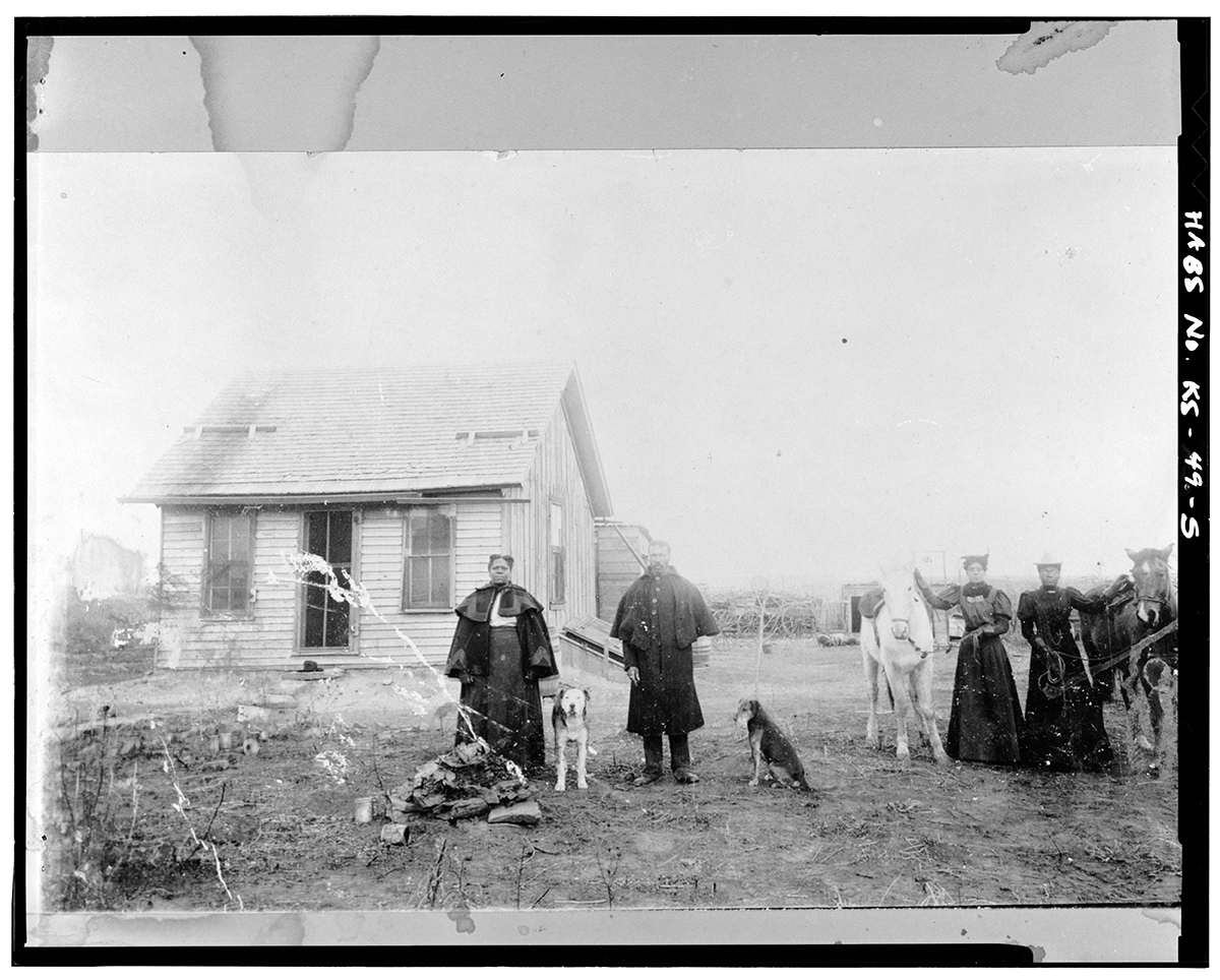 African Americans who migrated from States along the Mississippi River to Kansas in the late 19th century following the Civil War, in front of a home in Nicodemus, Kansas. 