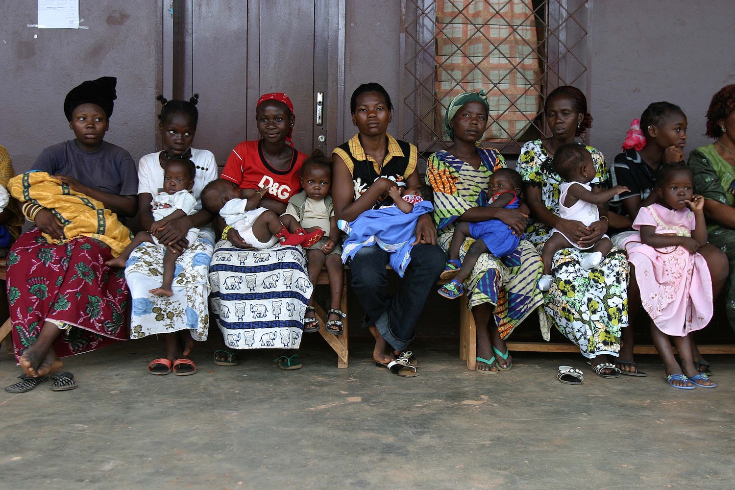 Women and children seated in a row, waiting to see a doctor