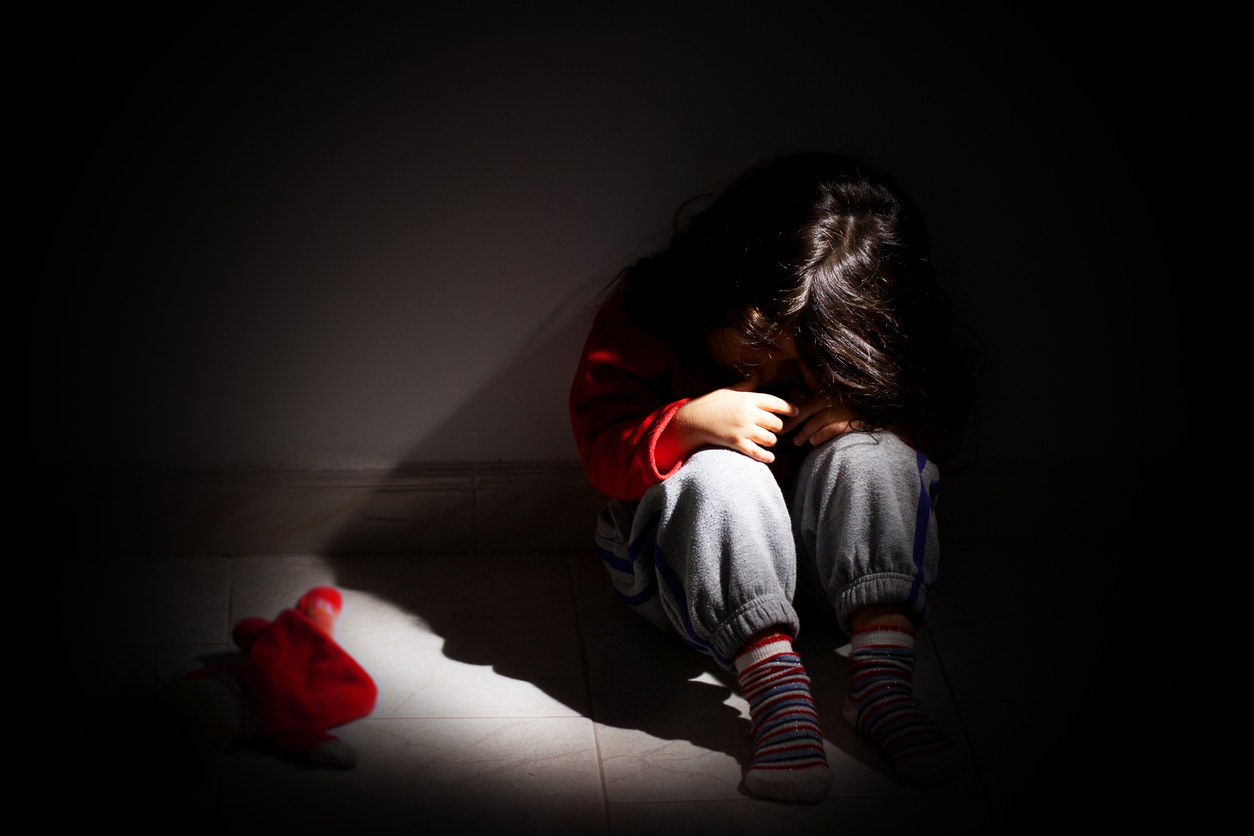 Dark, child huddled on floor