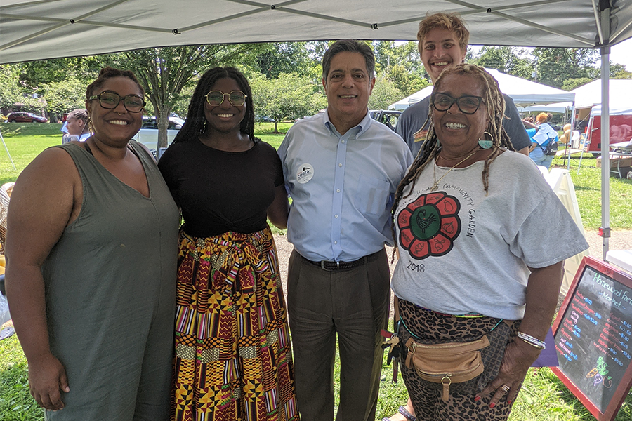 Group of five people photographed in front of a garden at Sankofa Village Community Garden.