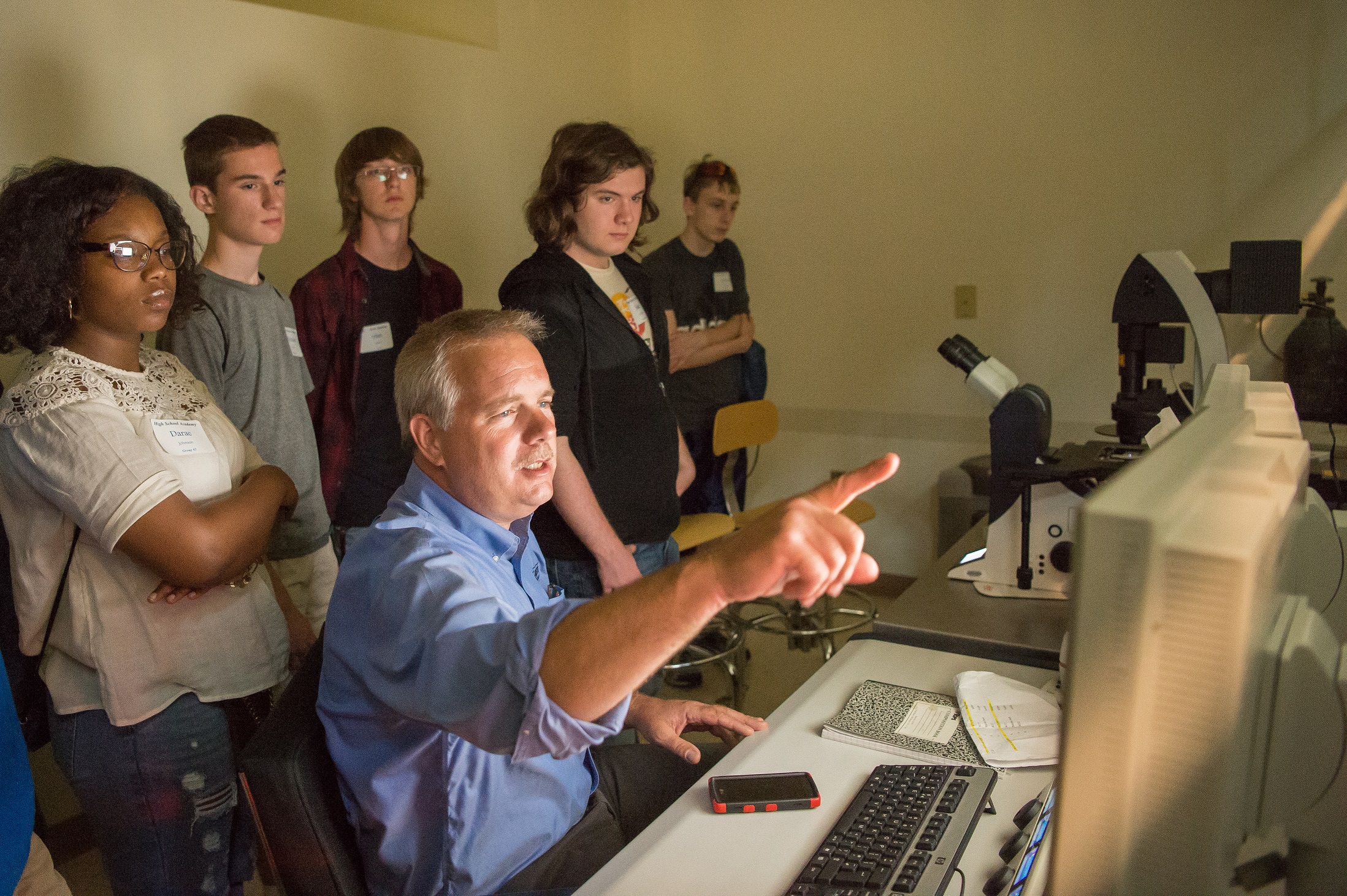 Jerry Magraw, senior technician in Penn State Behrend's School of Science, instructs students on how to use the confocal microscope during the college's High School Academy. 