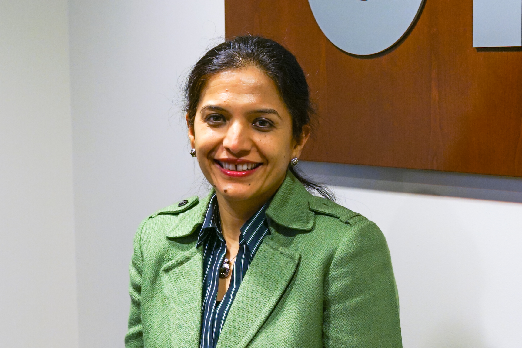 Woman smiles for camera in green jacket.