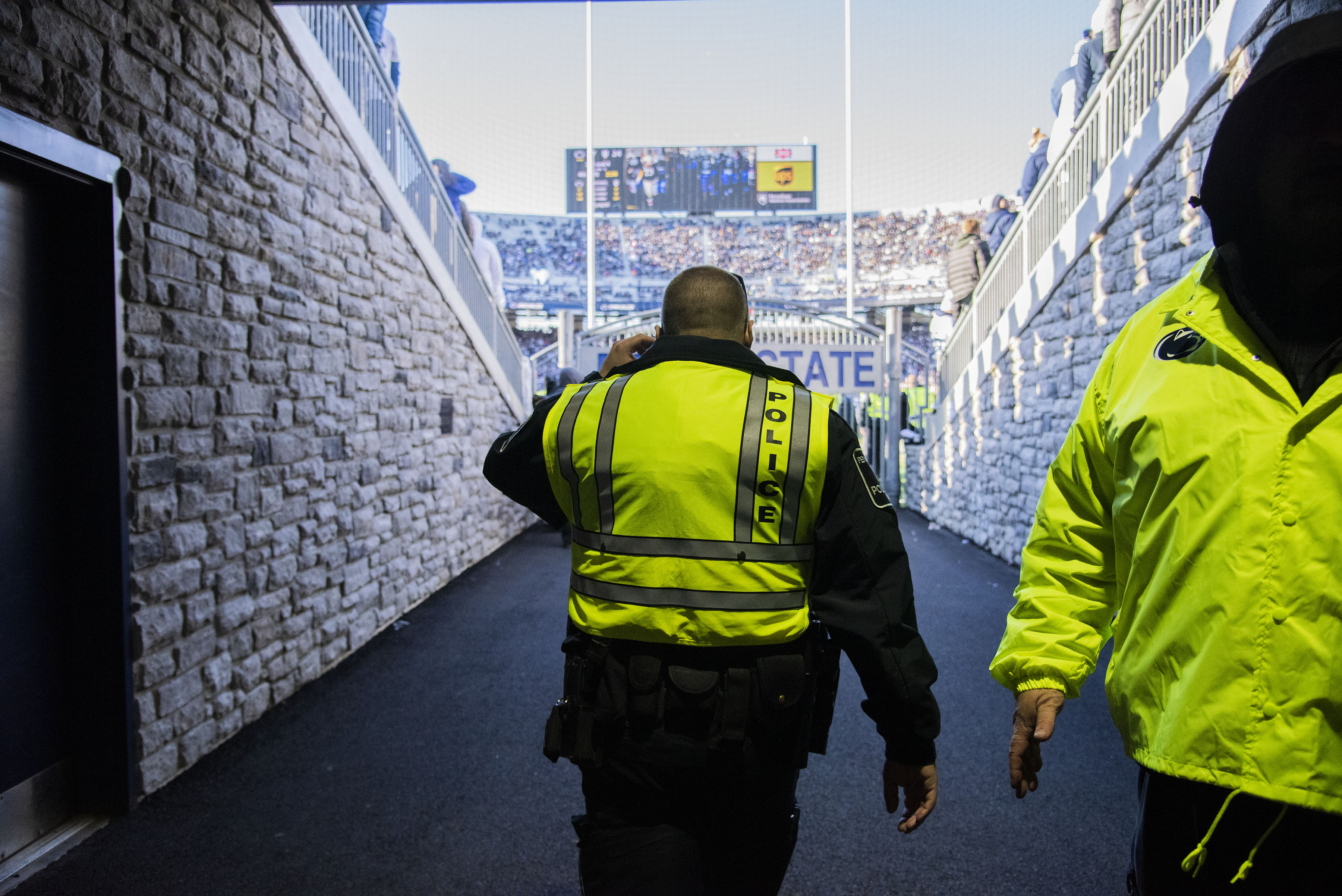 A Penn State Police officer stands in the tunnel at Beaver stadium looking out onto the football field.