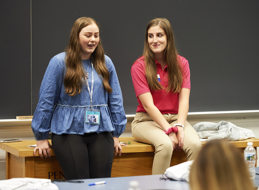 An incoming student and orientation leader sit on a desk