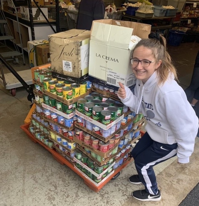 Zoe Cykosky standing next to pallet of donated goods