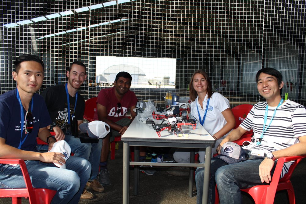 Four men and a women sit around a table with drones on it.