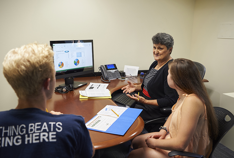 Daad Rizk, director of Penn State's Financial Literacy and Wellness Center, assists students from her office in Grange Building at University Park. 