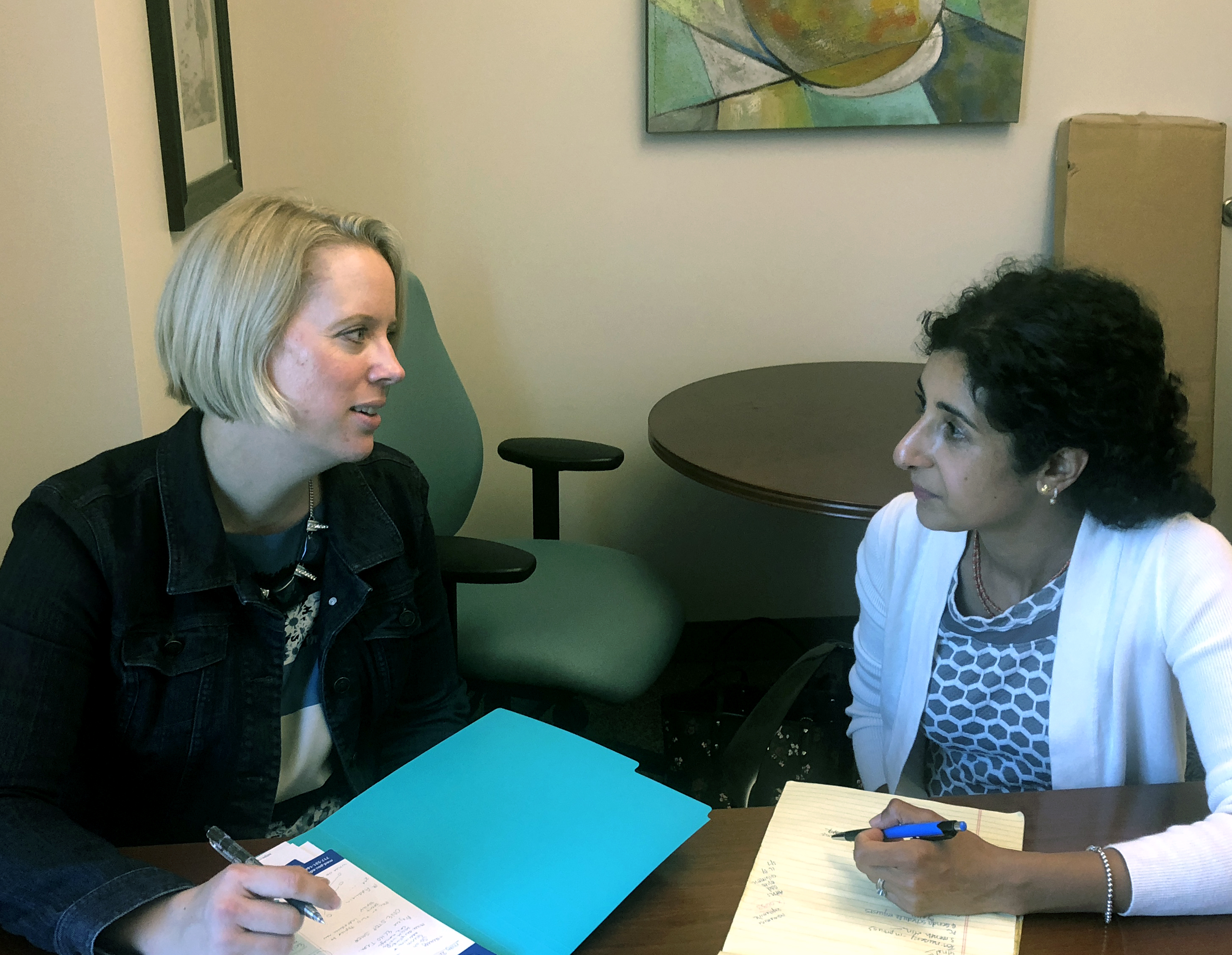 Two women sit and talk at a desk