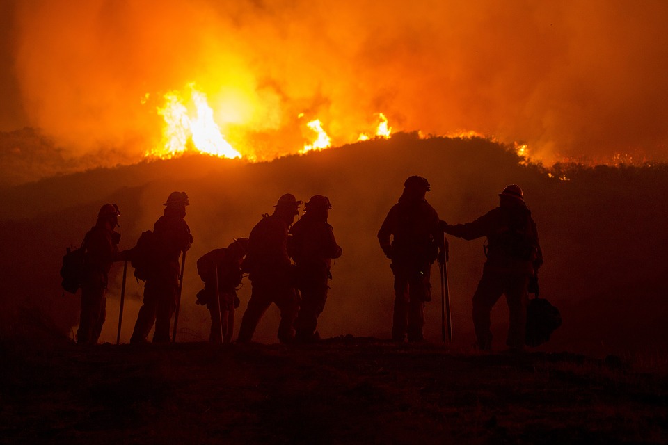 silhouette of firefighters in front of wildfire