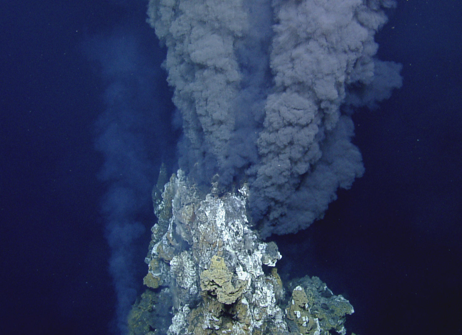 Super-heated water emerges from a hydrothermal vent in a dark plume