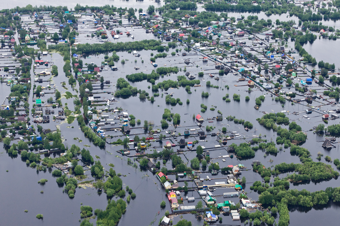 Tops of houses and trees peek through the waters of a flooded river