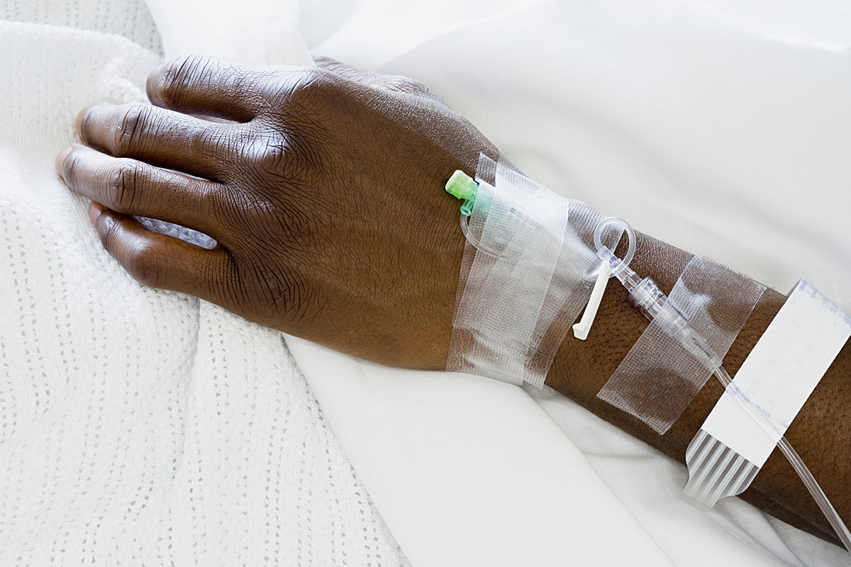 An image of a hand of a Black patient in the hospital receiving intravenous fluids. 