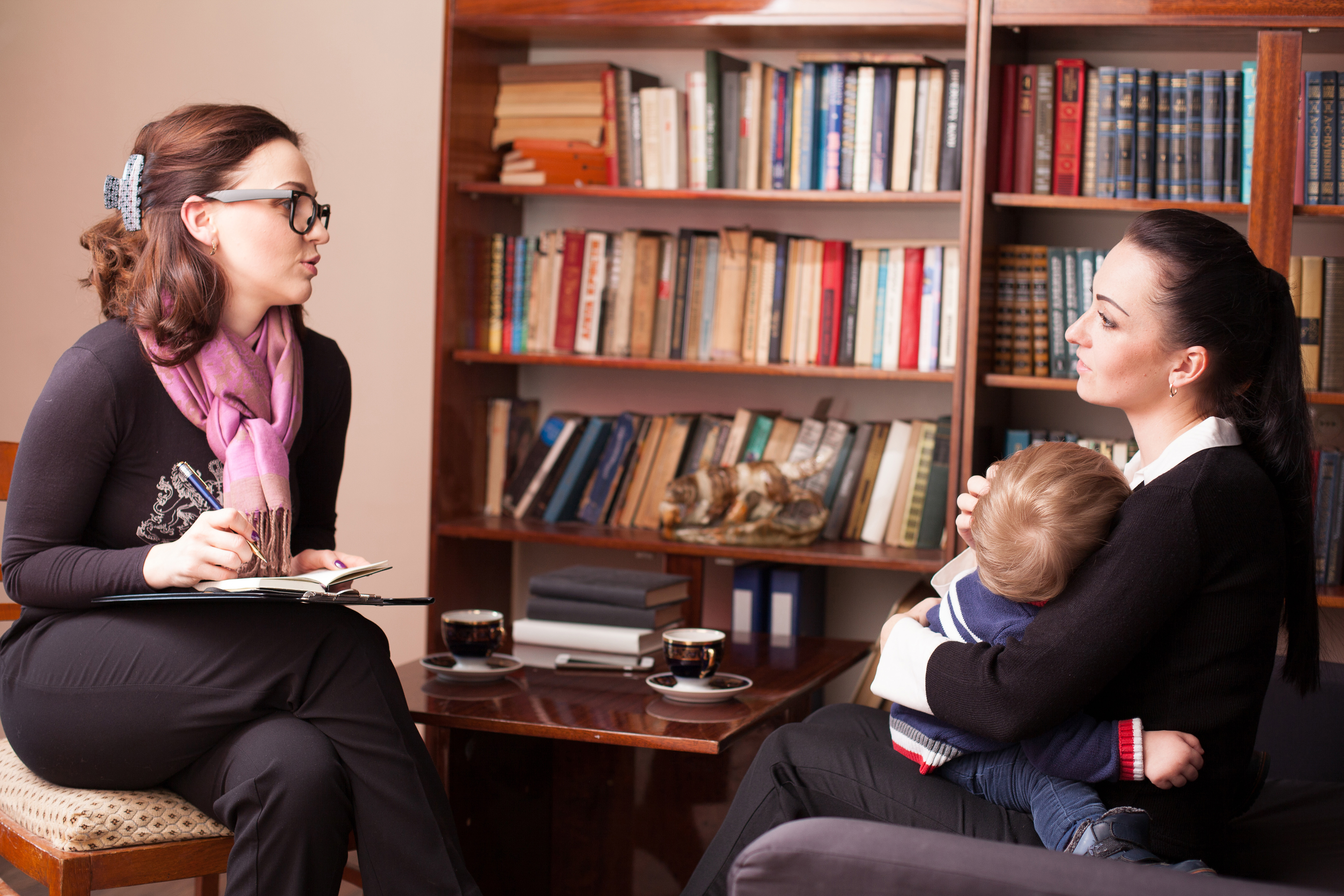 Woman talking to woman holding baby in office