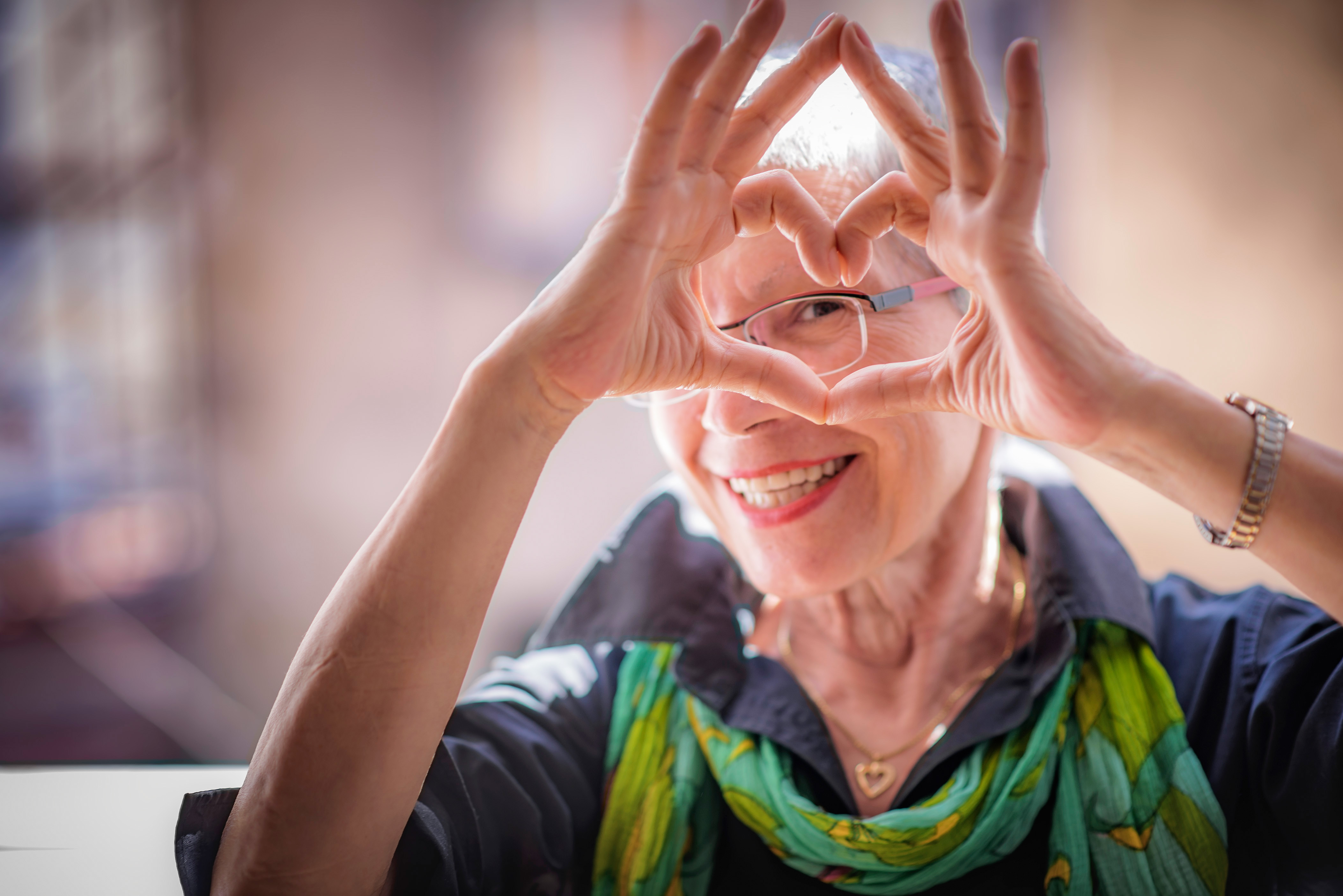 Older woman making a heart shape with her hands