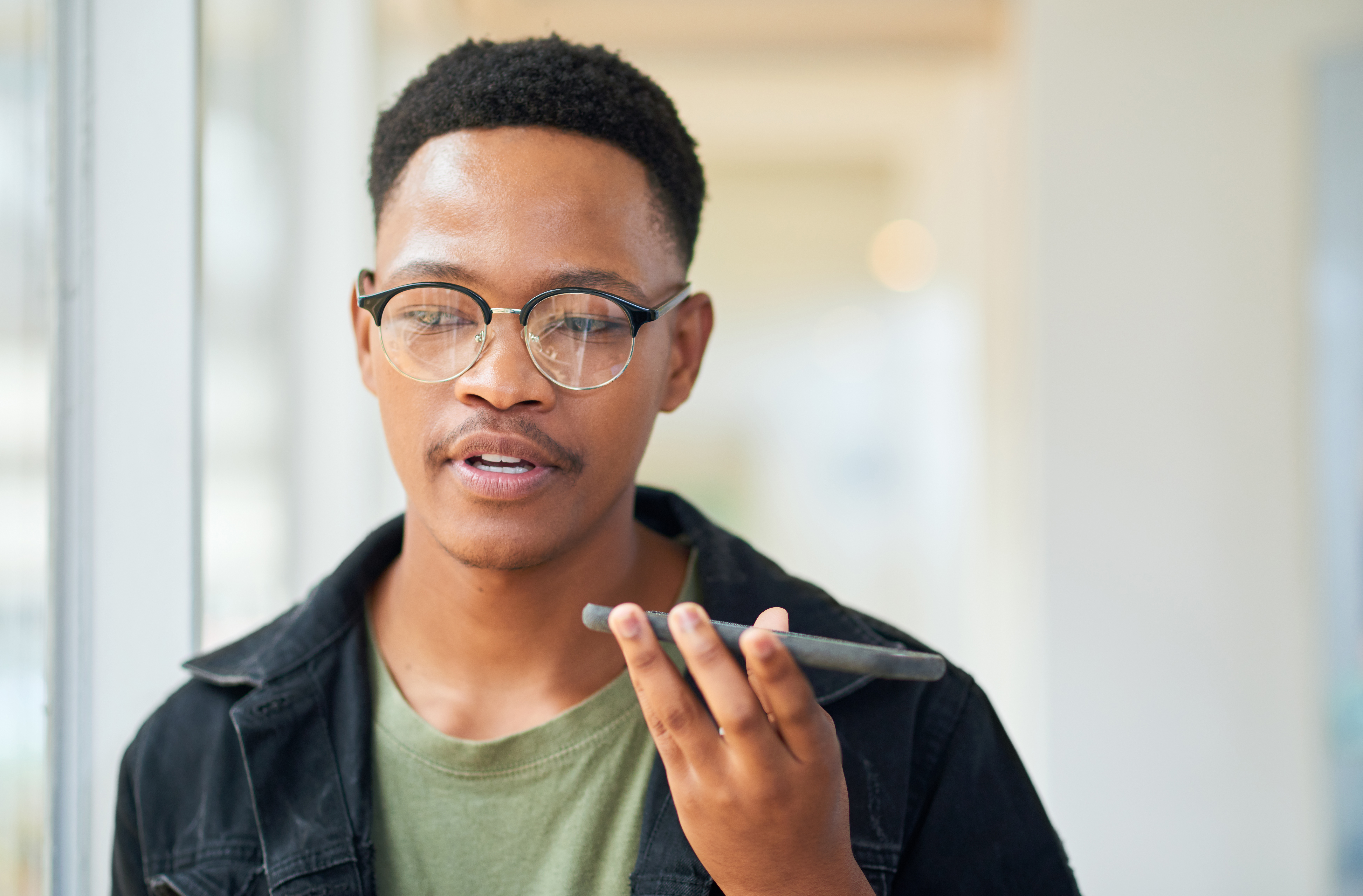 Man speaking into a cellphone in his hand as he walks