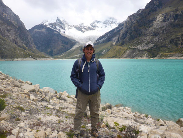 man standing in front of lake and mountains in Peru