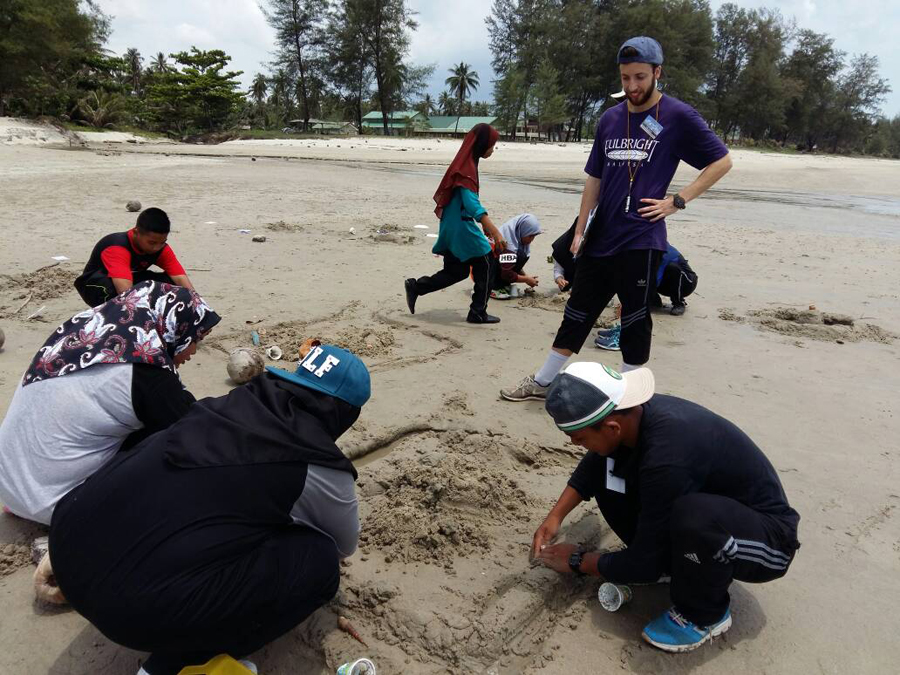 Conor Higgins watches several students as they build in the sand, part of a teaching activity