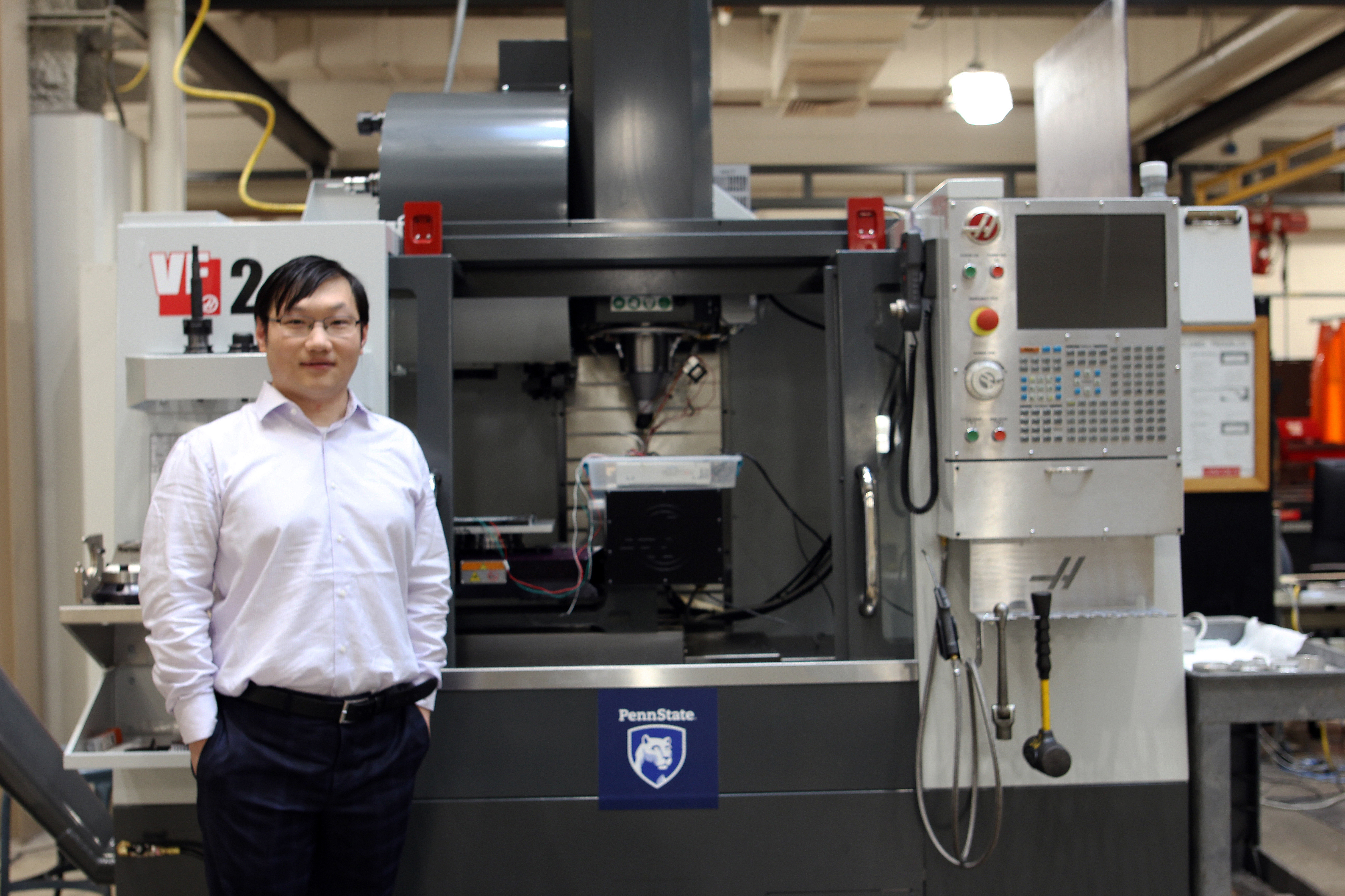 A man standing in a lab in front of a machine on the floor.