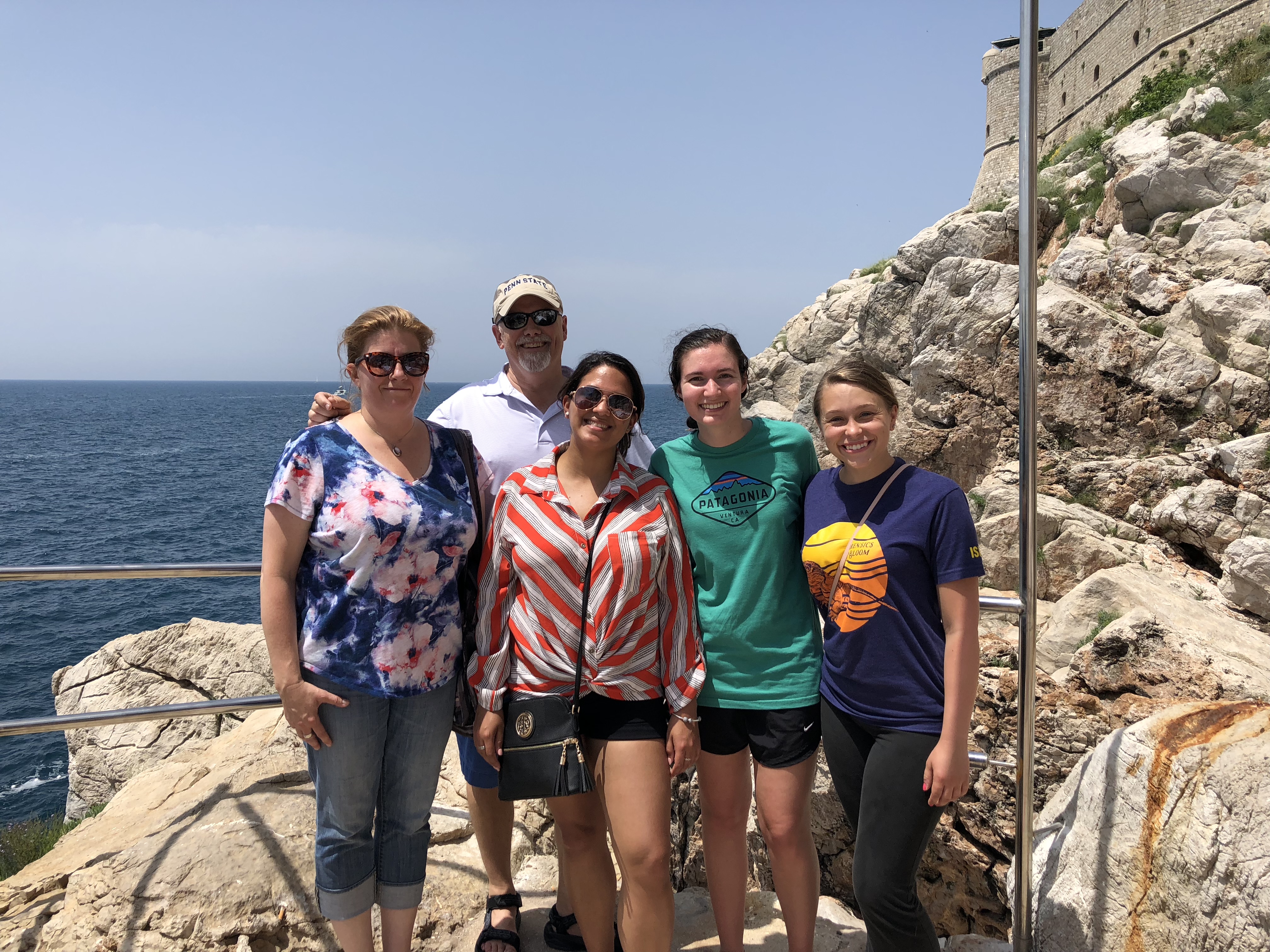 A group of people posing for the camera at a rocky beachfront in Croatia