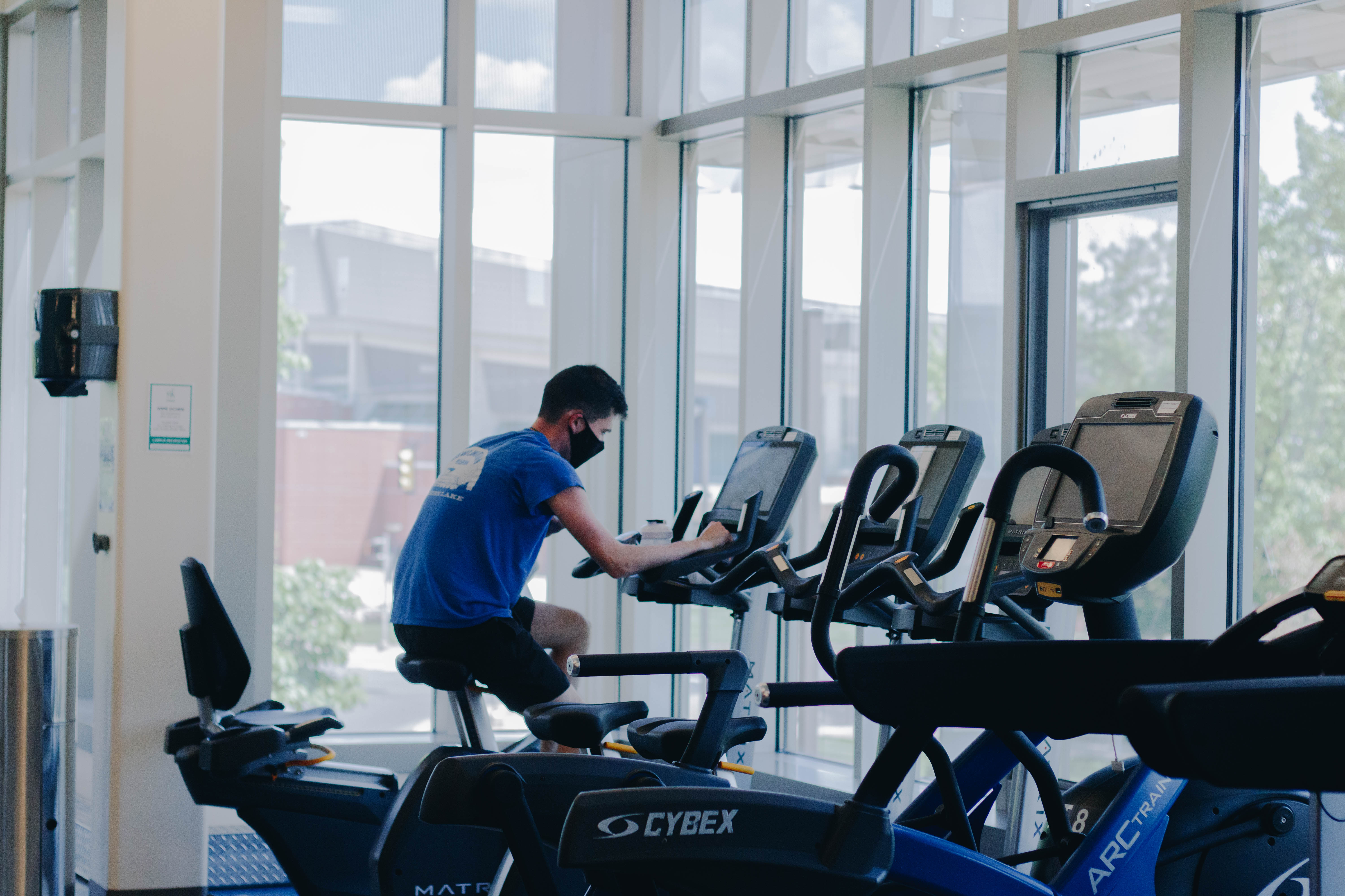 A student working out on a bike wearing a mask