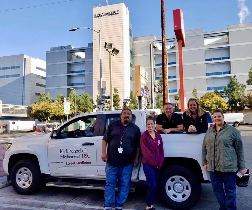 Brett Feldman and some of his team members stand by a white pickup truck in front of a hospital in LA