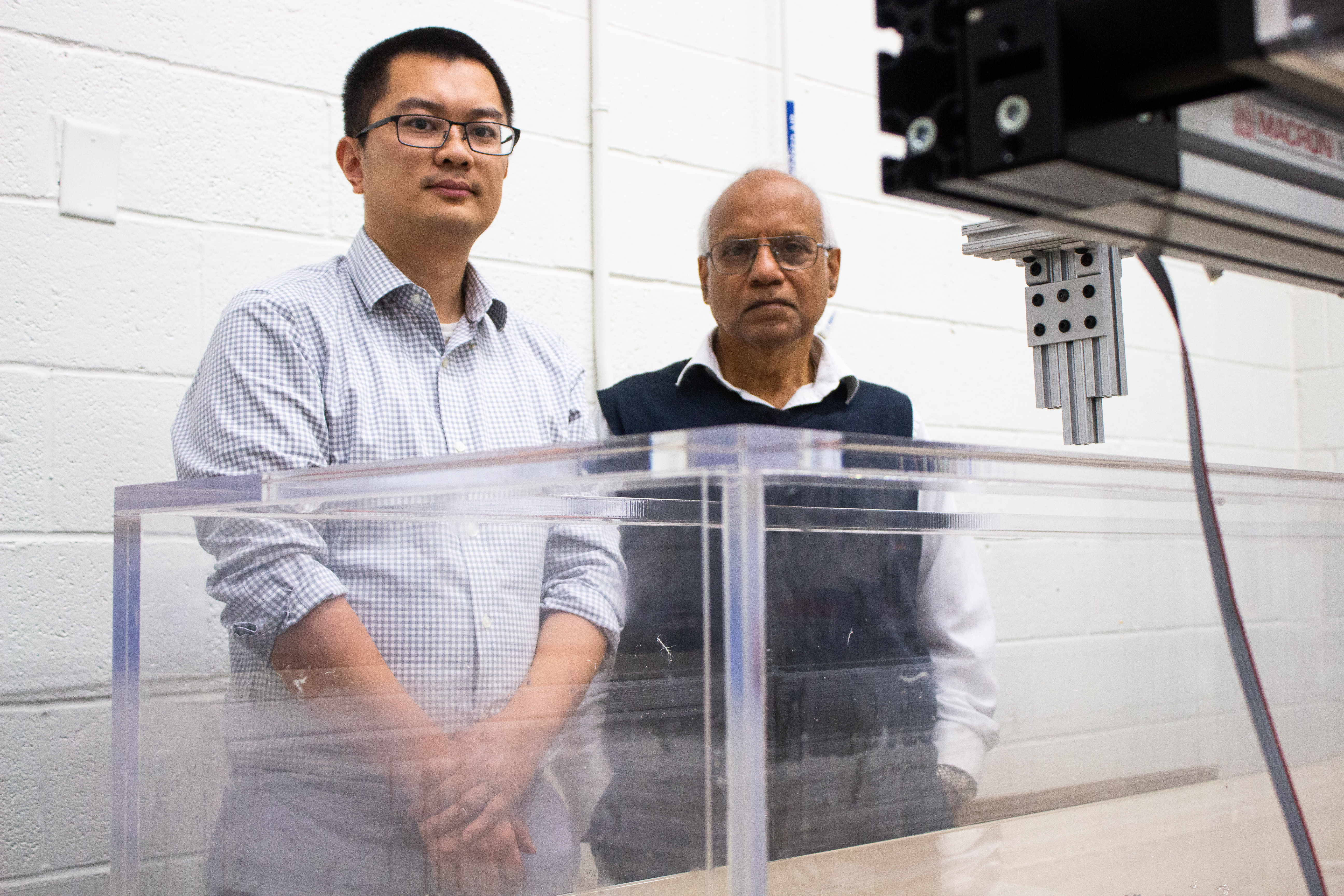 Two men stand in front of a tank of water in a research laboratory. 