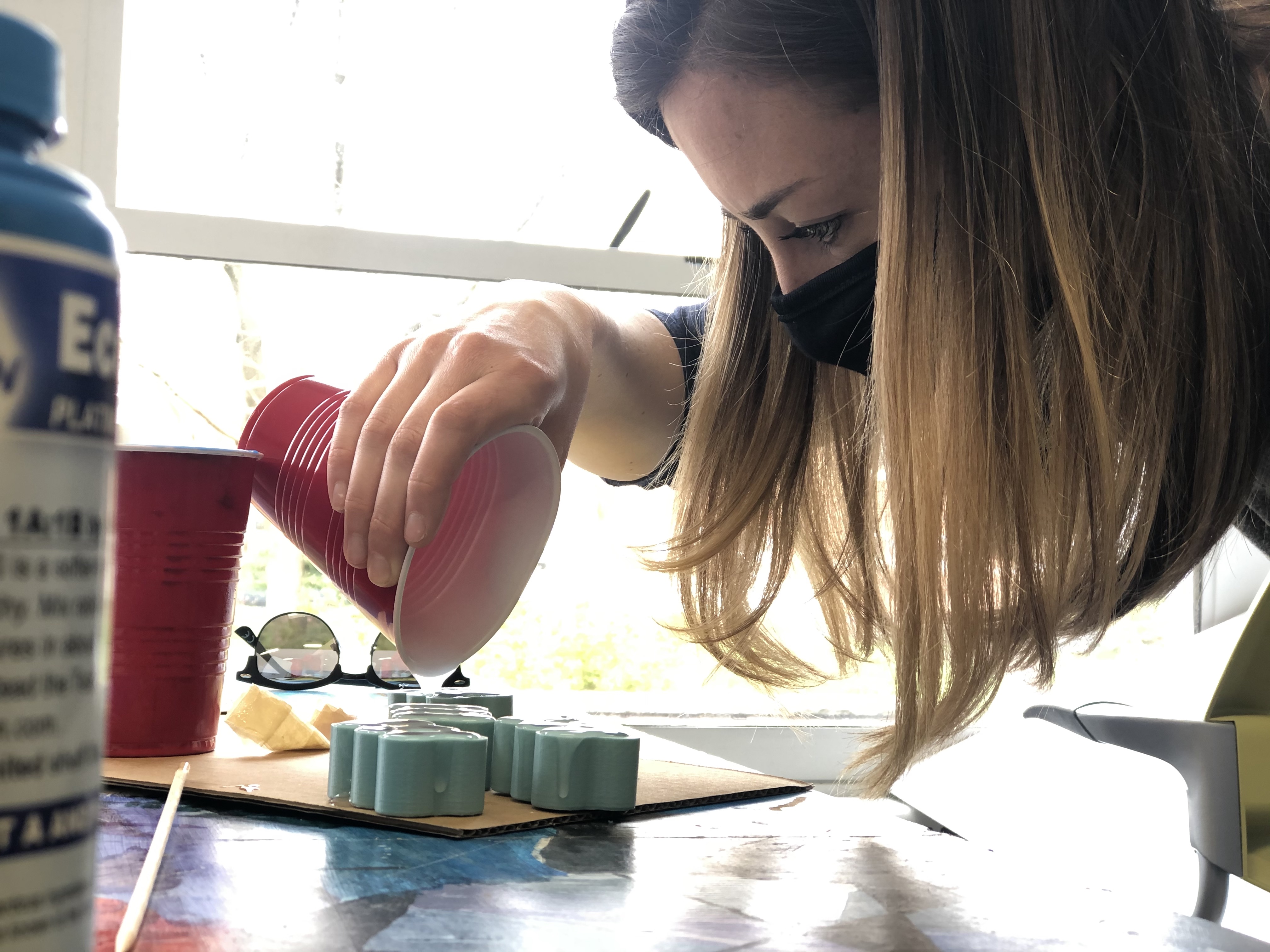 A female professor pours silicone into molds to create earpieces for disposal stethoscopes. 