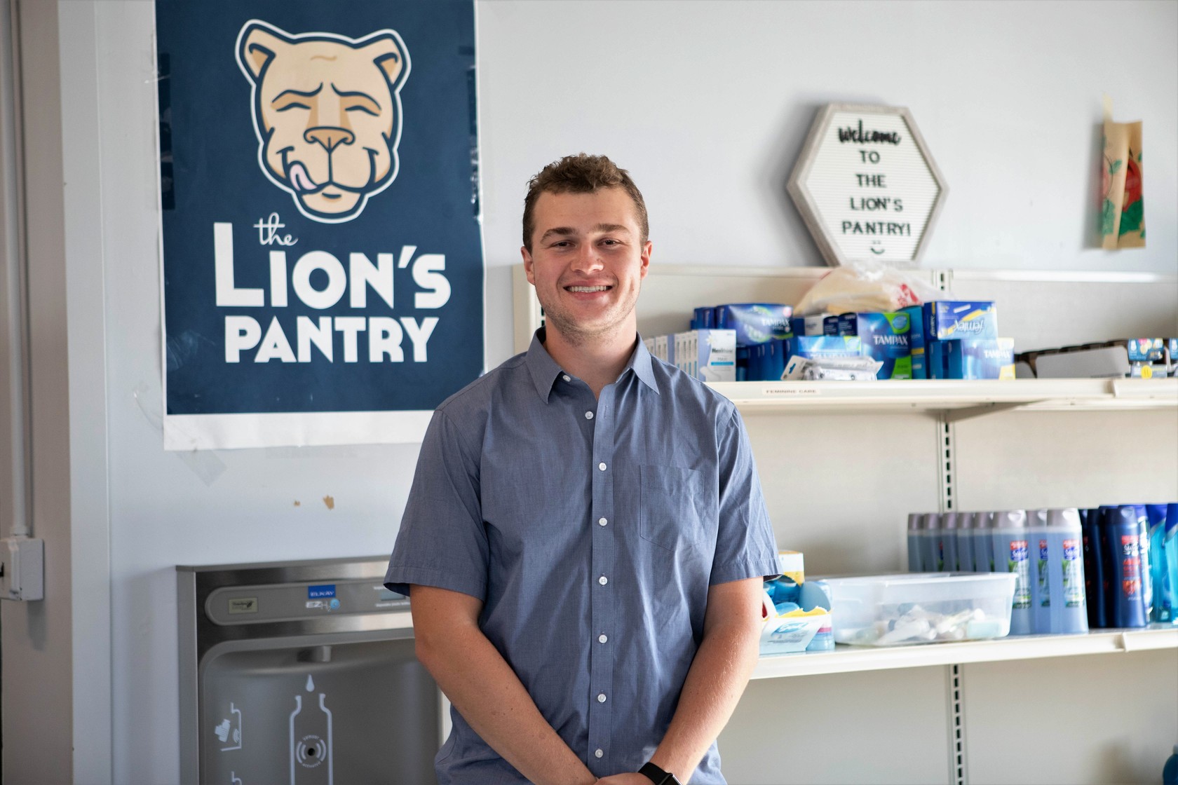 Spencer Wallace stands in front of the Lion's Pantry banner